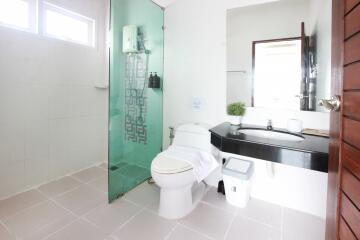 Modern bathroom with glass shower, sink, toilet and large mirror