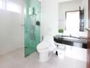 Modern bathroom with glass shower, sink, toilet and large mirror