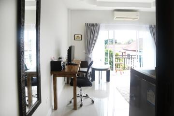 Bright living room with a desk, chair, mirror, and balcony view