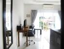 Bright living room with a desk, chair, mirror, and balcony view