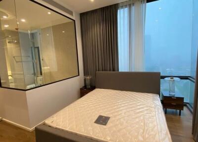 Modern bedroom with a large window, featuring an adjoining glass-walled bathroom