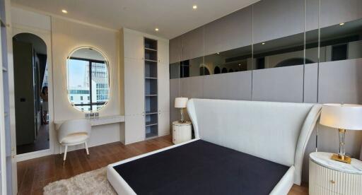 Modern bedroom with large mirror, bed frame, and nightstands