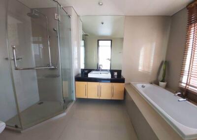 Modern bathroom with glass shower, bathtub, and vanity with mirror