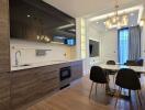 Modern kitchen and dining area with wooden cabinets, large windows, and elegant lighting fixtures