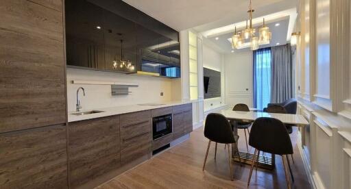 Modern kitchen and dining area with wooden cabinets, large windows, and elegant lighting fixtures