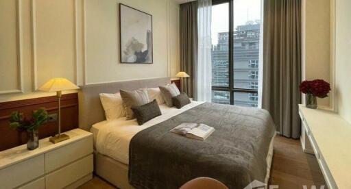 Spacious bedroom with city view, featuring a large bed, bedside tables with lamps, and modern decor