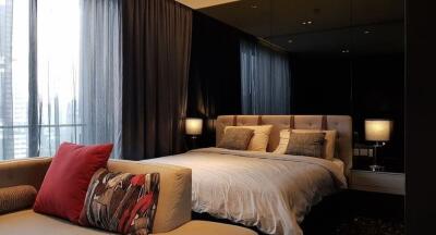 Modern bedroom with a large bed, upholstered headboard, bedside lamps, and large windows with curtains.