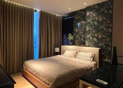 Modern bedroom with dark floral wallpaper, large window with drapes, and double bed with beige bedding