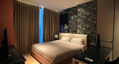 Modern bedroom with dark floral wallpaper, large window with drapes, and double bed with beige bedding