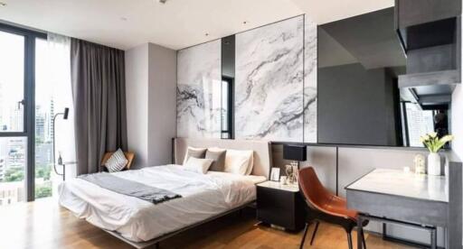 Modern bedroom with large window, marble feature wall, and work desk