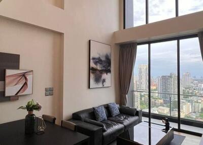 Living room with high ceiling and large windows overlooking a cityscape