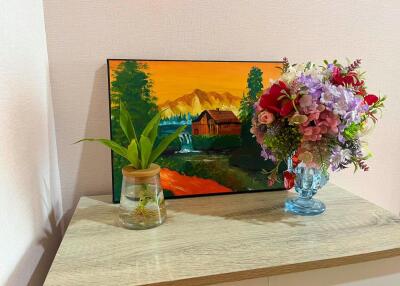 Decorative shelf with a painting, plant, and floral arrangement