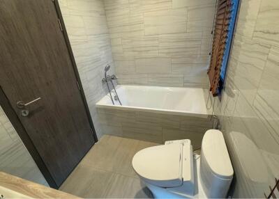 Modern bathroom with bathtub, toilet, and wooden blinds on window