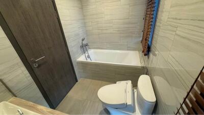 Modern bathroom with bathtub, toilet, and wooden blinds on window