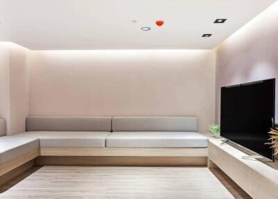 Modern living room with minimalist décor featuring a large flat-screen TV and built-in seating