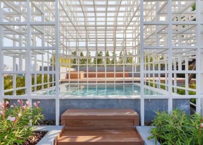 Modern outdoor pool area with geometric white structure and lush greenery