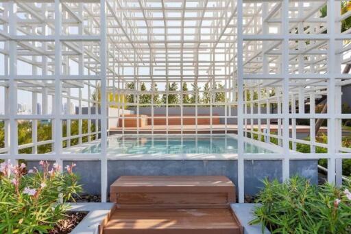 Modern outdoor pool area with geometric white structure and lush greenery