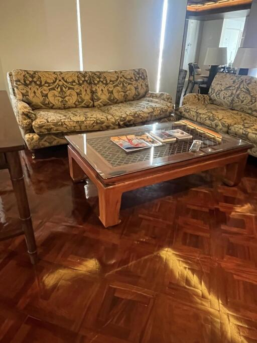 Living room with patterned couches and a glass-top coffee table