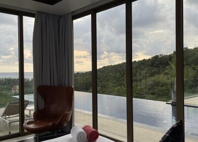 Bedroom with large windows overlooking pool and scenic view