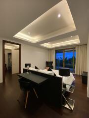 Modern bedroom with dark wood flooring, an elegant bed, a desk, and large windows.