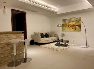 Modern living room with sofa, wall art, floor lamp, and a small dining area