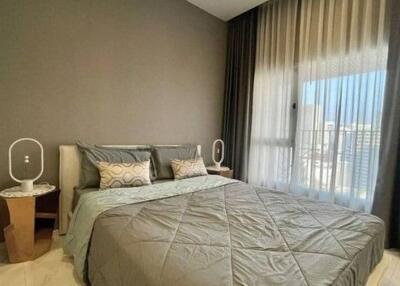 Modern bedroom with double bed, bedside tables, and large windows with curtains