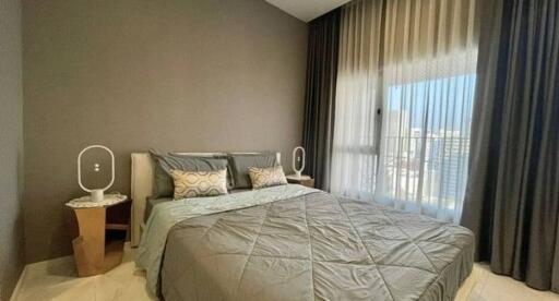 Modern bedroom with double bed, bedside tables, and large windows with curtains