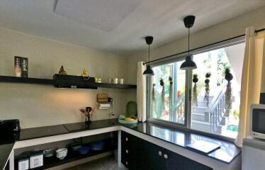 Modern kitchen with black countertops, open shelves, and large window