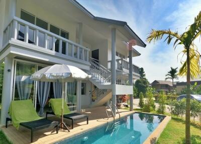 Exterior view of a modern two-story house with a pool and outdoor seating area