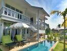 Exterior view of a modern two-story house with a pool and outdoor seating area