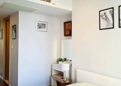 A bright bedroom with hallway view and framed pictures on the wall.