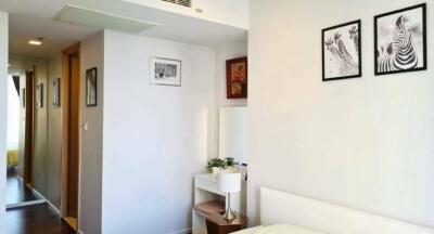 A bright bedroom with hallway view and framed pictures on the wall.