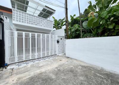 Modern white house with gated entrance and tropical surroundings