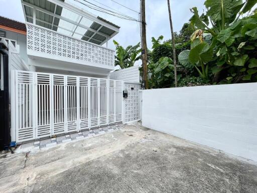 Modern white house with gated entrance and tropical surroundings
