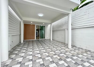 Covered garage with tiled flooring and white pillars
