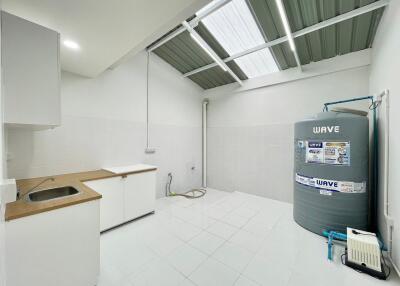 Well-lit utility room with a water tank and washing area