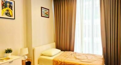 Cozy bedroom with single bed, light brown curtains, and artworks on the wall