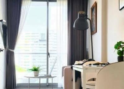 Well-lit living room with large window, small table, TV, and desk