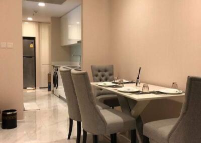 Modern dining area with gray chairs and a table, adjacent to the kitchen