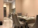 Modern dining area with gray chairs and a table, adjacent to the kitchen