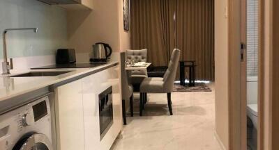 Modern kitchen leading to a dining area with gray chairs