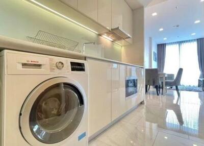 Modern laundry room with washer, cabinets, dining area in the background