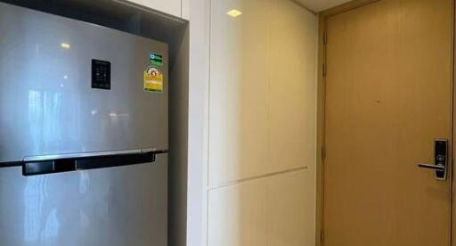 A modern kitchen entry with a refrigerator and sleek cabinetry