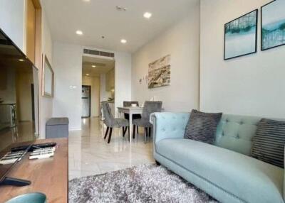 Modern living room with a comfortable sofa, wall art, and a view towards the dining area and kitchen