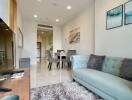 Modern living room with a comfortable sofa, wall art, and a view towards the dining area and kitchen