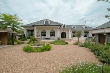 Front view of a house with a gravel yard and fountain