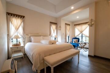 Cozy bedroom with large bed, bench, and natural lighting