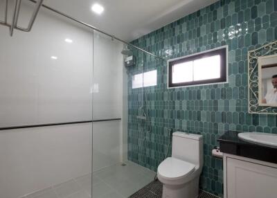 Modern bathroom with glass shower, toilet, and vintage mirror