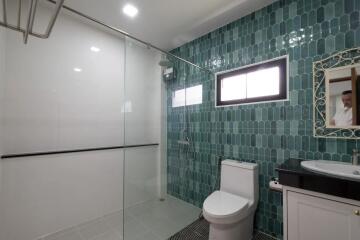 Modern bathroom with glass shower, toilet, and vintage mirror