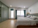 Spacious bedroom with green cabinets and large window
